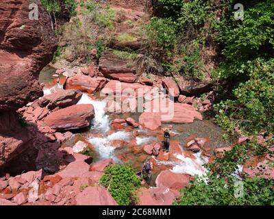 Due giovani uomini volano pesca in un fiume pittoresco in un canyon di rocce di pelite rossa. Fiume Cians, Gorges du Cians, Beuil, Alpes-Maritimes, Francia. Foto Stock