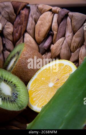 Metà di limone di kiwi e acari e una foglia di aloe vera in un cesto di legno. Foto Stock