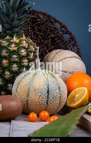 Fotografia di frutta commestibile: Arancio, melone di melone, lanterna cinese e una foglia verde di aloe vera, davanti ad un cesto piatto intrecciato Foto Stock