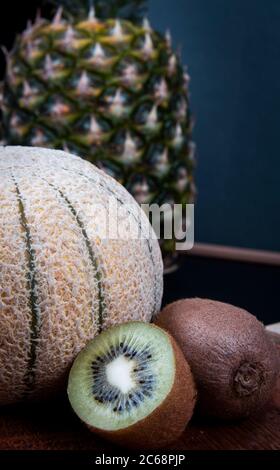 Un colpo vicino di alcuni frutti include un grande ananas, melone di miele e kiwis. Foto Stock