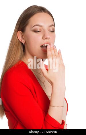 Una giovane donna d'affari in un vestito rosso uno sfondo isolato in bianco, annoiato e sbadigliato Foto Stock