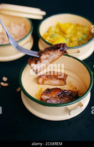 forchetta per raccogliere il maiale arrosto dalla scatola tiffin rotonda Foto Stock