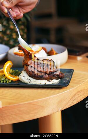 bastone di pollo arrosto con salsa di mandarino su purè di patate su piatto nero su tavolo di legno Foto Stock