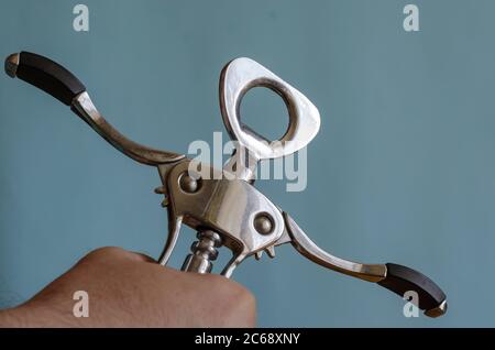 L'uomo adulto tiene in mano un cavatappi di metallo. Stappatura di bottiglie di vino. Maschio di razza europea, 43-45 anni. Utensili da cucina Foto Stock