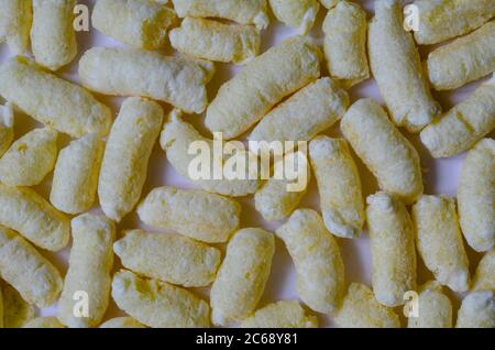 Croccanti ariosi, polsini di mais, spuntini di puffcorn sfondo. Shot dettagliato di puffcorn pronto per il consumo. Dolci croccanti. Foto Stock