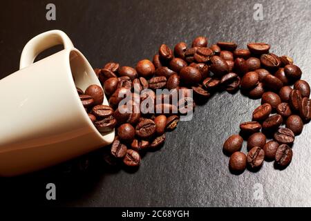 cospargere i chicchi di caffè e una tazza di caffè espresso su un tavolo scuro. Ristorante, bevande e caffè ancora vita Foto Stock