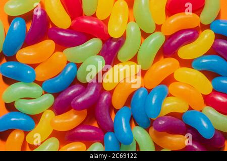 Jelly Beans assortiti bordo con copyspace su sfondo arancione. Foto Stock
