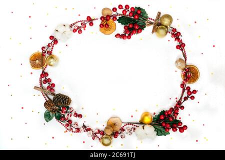 Cerchio cornice come corona da natale rosso e oro decorazione con frutti di bosco, palle, mele e fette d'arancia, cotone e noci. Sfondo bianco decorare Foto Stock