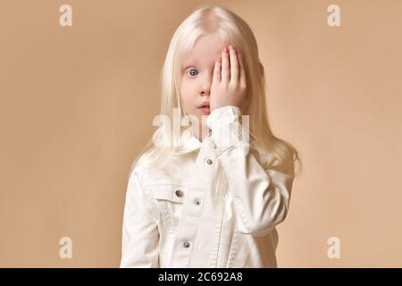 adorabile bella bambina con colore bianco dei capelli e la pelle chiuso un occhio e guardare la fotocamera isolato Foto Stock