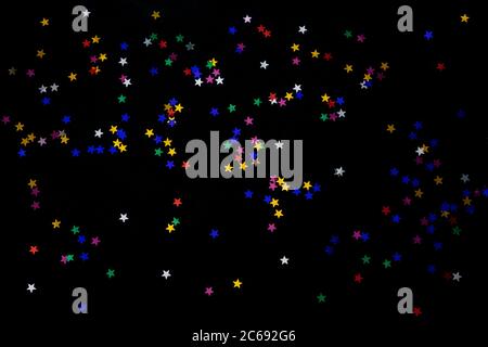 Stelle multicolore su sfondo nero. Sfondo festoso di colorate stelle di confetti su sfondo nero. Foto Stock