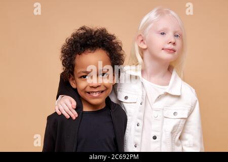 stretta amicizia tra due figli di diverse nazionalità, bella ragazza albina caucasica e ragazzo africano dalla pelle scura con capelli ricci, loro un Foto Stock