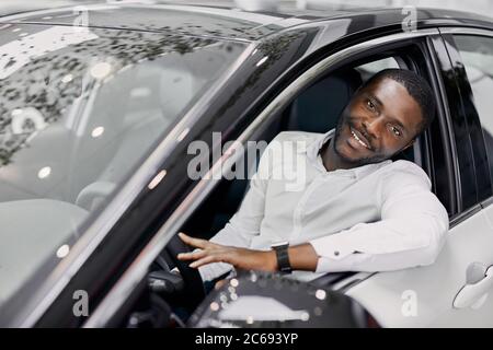 uomo d'affari siede all'interno di costoso automobile di lusso in concessionaria, fa l'acquisto, i sogni diventano realtà Foto Stock