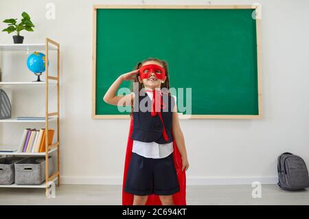 Bambini a scuola. Il supereroe della scuola ride divertente in una classe scolastica. Foto Stock