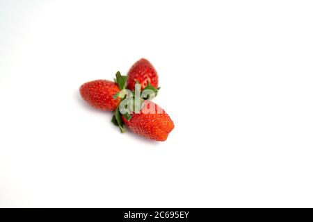 Quattro fragole rosse fresche mature con foglie isolate su sfondo bianco. Vista dall'alto. Messa a fuoco selettiva. Foto Stock