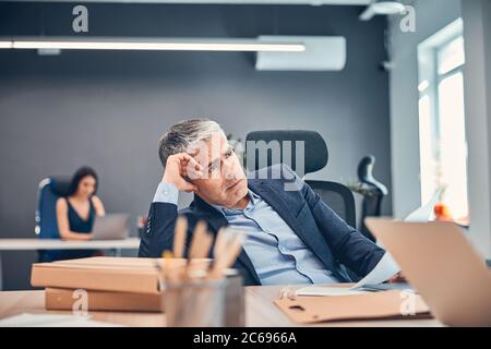 Un uomo d'affari in eccesso frustrato e stressato nel suo ufficio Foto Stock