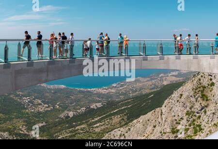 I turisti camminano attraverso il nuovo Skywalk sulla montagna di Biokovo. Ampia vista dall'ingresso, città e mare visibili in lontananza Foto Stock