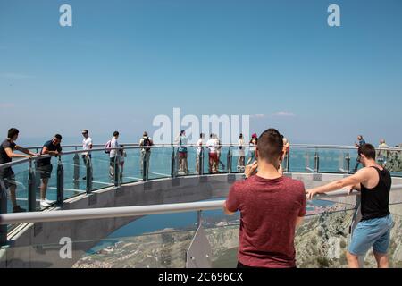 I turisti camminano attraverso il nuovo Skywalk sulla montagna di Biokovo. Due uomini in primo piano scattano una foto, ammirando la distanza Foto Stock