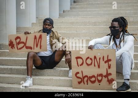 I manifestanti hanno in mano bandiere con il motto del movimento nero per i diritti civili 'Black Lives Matter', 'Do't Shoot' per mostrare la loro solidarietà con l'Africano Foto Stock