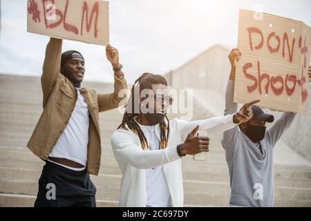 I manifestanti hanno in mano bandiere con il motto del movimento nero per i diritti civili 'Black Lives Matter', 'Do't Shoot' per mostrare la loro solidarietà con l'Africano Foto Stock