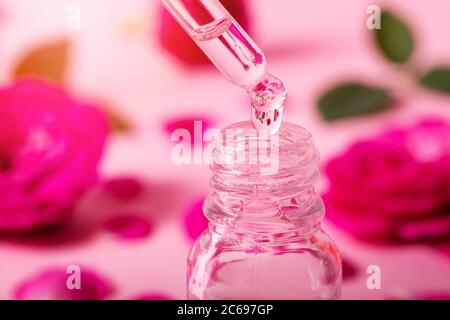 contagocce con olio essenziale di fiori di rosa goccia sopra la bottiglia Foto Stock