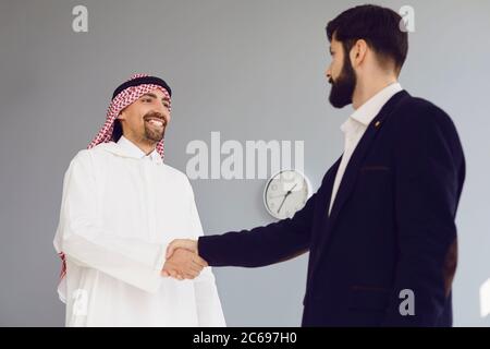 Stretta di mano di uomini d'affari arabi ed europei in ufficio. Foto Stock