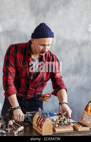 uomo in camicia , cappello e pantaloni che contano i suoi attrezzi in officina. primo piano foto Foto Stock