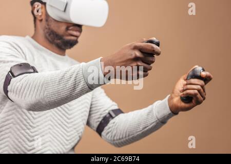 Di carnagione scura millenario il turista in un abbigliamento informale con gli occhiali con testa-display montato per smart phone, operando con i controller in mani, il DOI Foto Stock