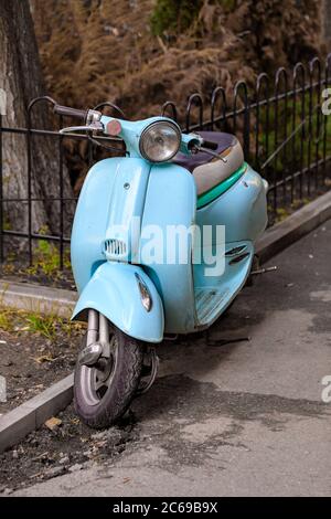 Scooter retrò azzurro parcheggiato sulla vecchia strada della città. Stile vintage. Spazio di copia. Foto Stock