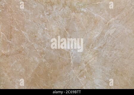 Struttura insolita di marmo beige antico con macchie beige biancastre, crepe e graffi. Superficie lucidata. Foto Stock