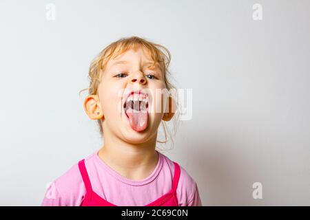 Ritratto di bambina dolce come lei sta attaccando la sua lingua fuori, lingua strisciante. Foto Stock