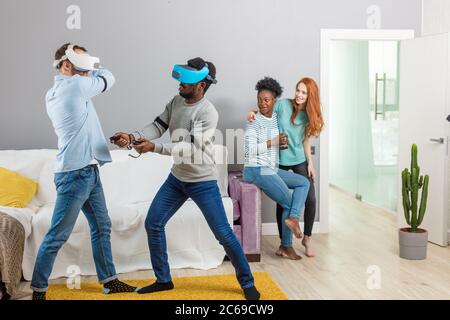 International diversi studenti in appoggio insieme con gli occhiali della realtà virtuale di una casa, due giovani interracial uomini ragazze divertente Foto Stock