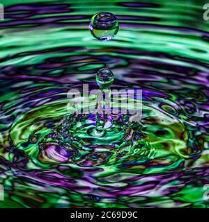 Spruzzi d'acqua, goccia con un polivalente colore blu verde iridescente trasparente ripple splash Foto Stock