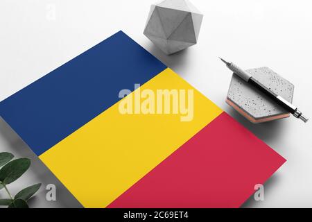 Bandiera Ciad su sfondo di carta minimalista. Lettera nazionale di invito con penna elegante su pietra. Concetto di comunicazione. Foto Stock
