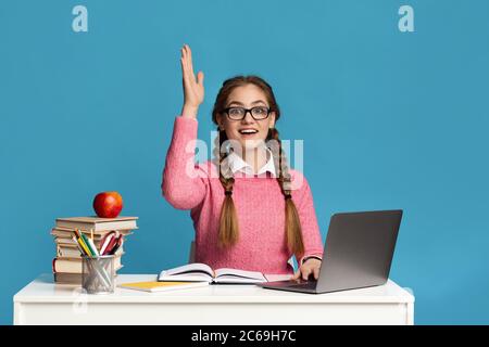 La ragazza adolescente intelligente con gli occhiali alza la mano Foto Stock