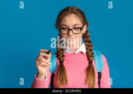 Ragazza adolescente con i pigtail e gli occhiali scrive con marcatore sullo schermo Foto Stock