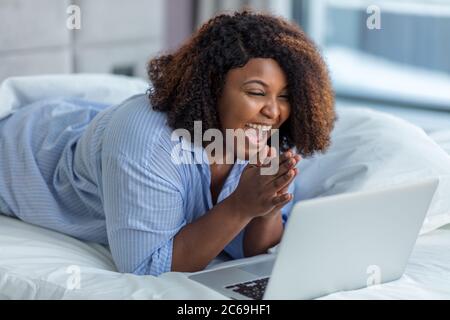 ragazza positiva che ride a spettacolo divertente mentre riposa nel letto comodo. primo piano photo.emotion e feeling Foto Stock