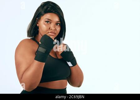 Pump african american misto donna di razza mostrando la sua fiducia durante l'allenamento in studio su sfondo bianco. Fitness, Sport, modello Plus-size e Bod Foto Stock