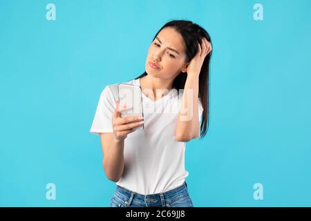 Giovane bella donna confusa con il telefono cellulare Foto Stock