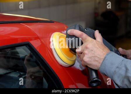 Vista parziale di un uomo che tiene una macchina elettrica per la lucidatura di automobili Foto Stock