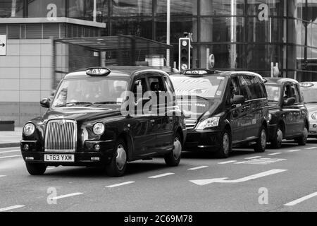 LONDRA, UK - 9 MARZO 2014: Una fila di Taxi ha sillato fuori alcuni edifici a Londra durante il giorno Foto Stock