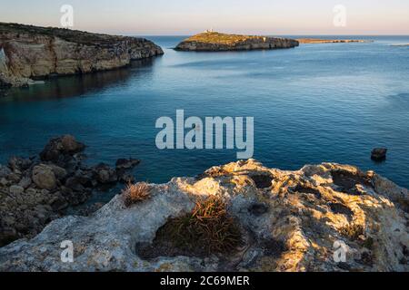 Vista serale verso Selmunet o sulle isole di Saint Paul e due uomini la pesca dalla barca, Malta Foto Stock