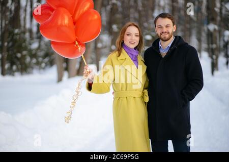 ritratto di felice caucasica donna e ragazzo che celebra san valentino insieme all'aperto. coppia vestito in cappotti godere di trascorrere il tempo insieme, tenere r Foto Stock