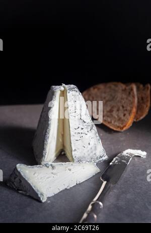 Una piramide di formaggio di capra ricoperta di cenere tagliata con toast di pasta acida Foto Stock