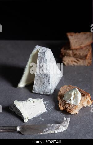 Una piramide di formaggio di capra ricoperta di cenere con pane di pasta acida Foto Stock