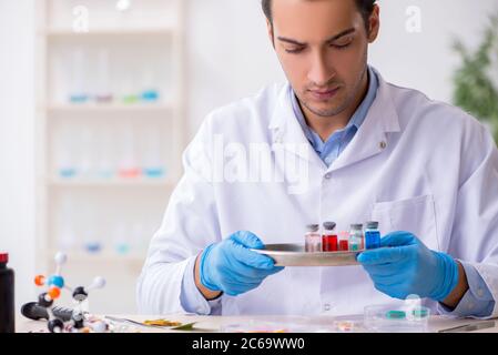 Giovane assistente di laboratorio maschile nel concetto di sintesi del farmaco Foto Stock
