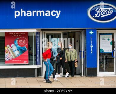 Edimburgo, Scozia, Regno Unito, 8 luglio 2020. Le maschere facciali sono la norma su Princes Street con sempre più persone che le indossano, soprattutto per andare nei negozi, anche se non diventano obbligatori nei negozi in Scozia fino a venerdì. Le giovani donne che indossano maschere facciali escono da Boots il negozio chimico Foto Stock