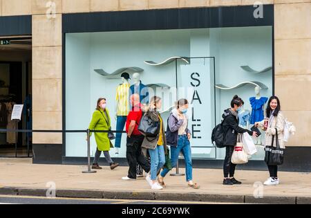 Edimburgo, Scozia, Regno Unito, 8 luglio 2020. Le maschere facciali sono la norma su Princes Street con sempre più persone che le indossano, soprattutto per andare nei negozi, anche se non diventano obbligatori nei negozi in Scozia fino a venerdì. Giovani donne che indossano maschere al di fuori del negozio di abbigliamento Zara Foto Stock