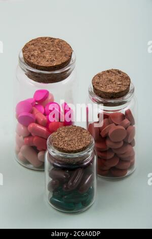 Pillole e capsule colorate all'esterno della confezione all'interno del contenitore in vetro della confezione. Foto Stock