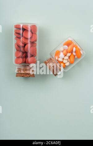 Pillole e capsule colorate all'esterno della confezione all'interno del contenitore in vetro della confezione. Foto Stock