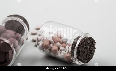 Pillole e capsule colorate all'esterno della confezione all'interno del contenitore in vetro della confezione. Foto Stock